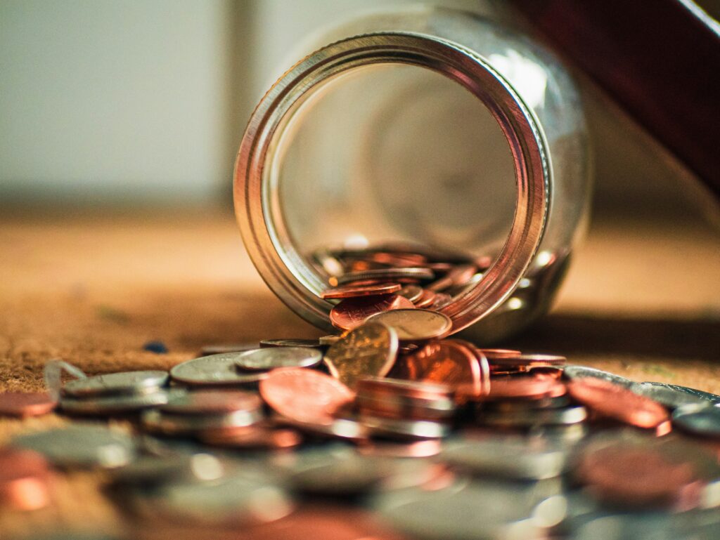 Coins spill out of a jar onto a table.